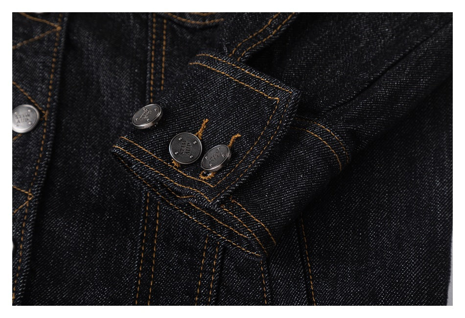 Close-up of a buttoned cuff and orange stitching on a black denim jacket.
