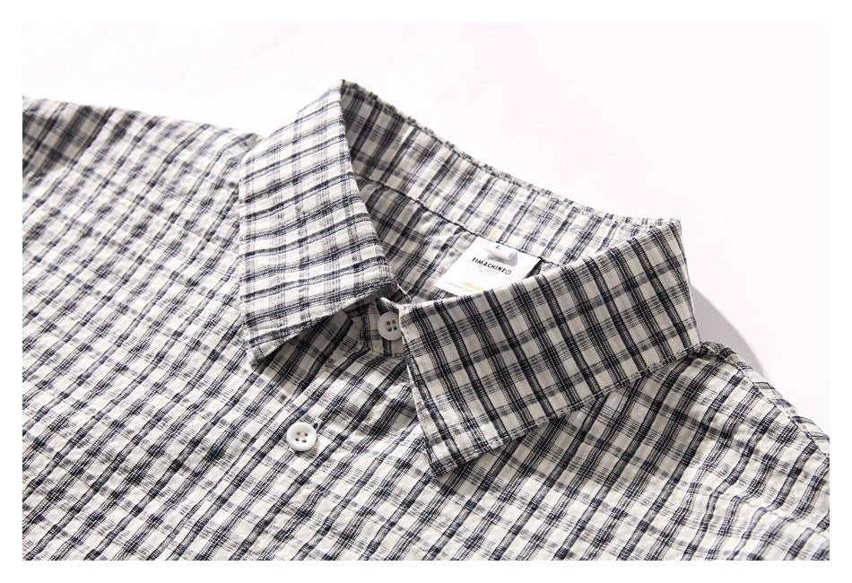 Close-up of a black-and-white plaid shirt collar, neckline label, and white buttons.