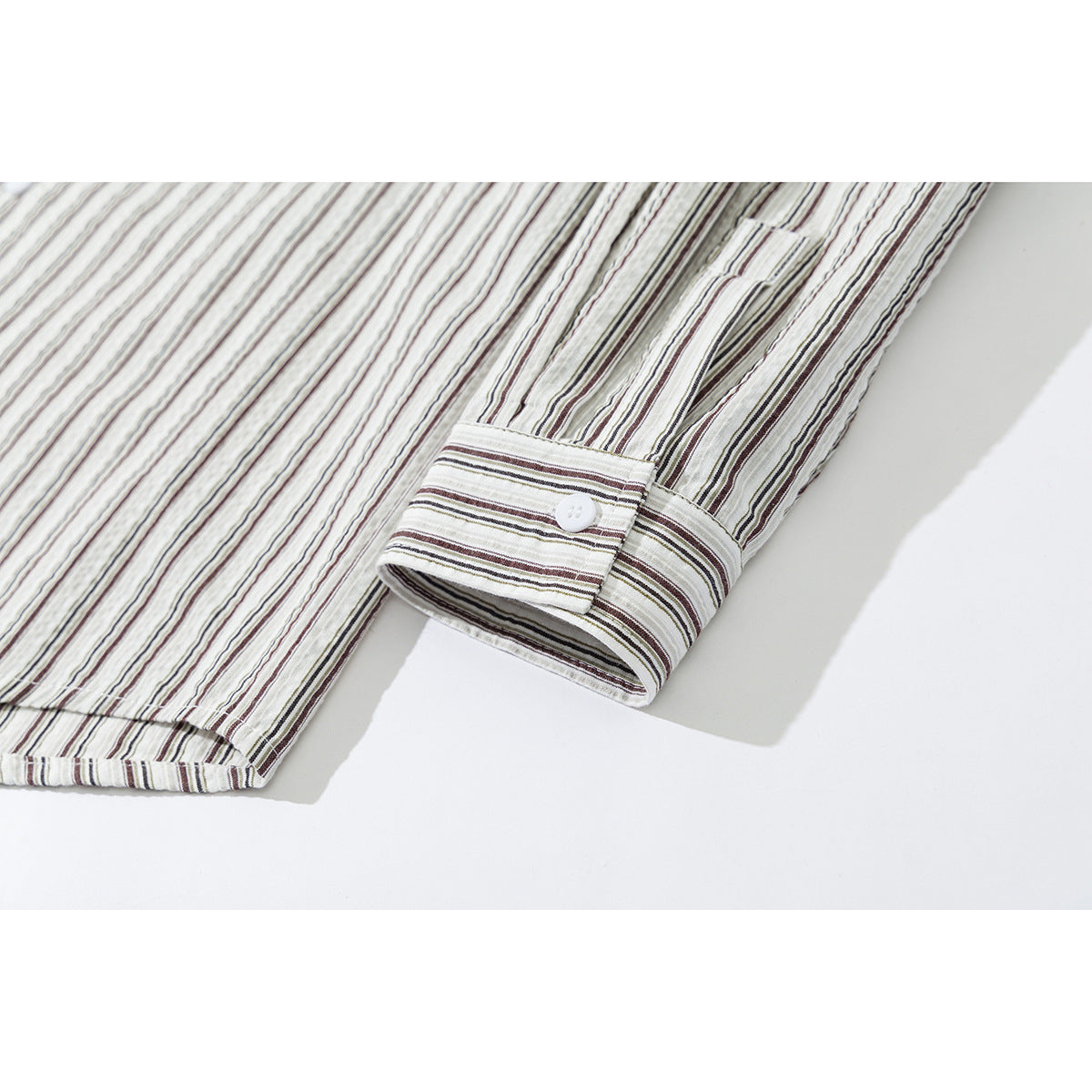 Close-up of a cream striped shirt sleeve and buttoned cuff.