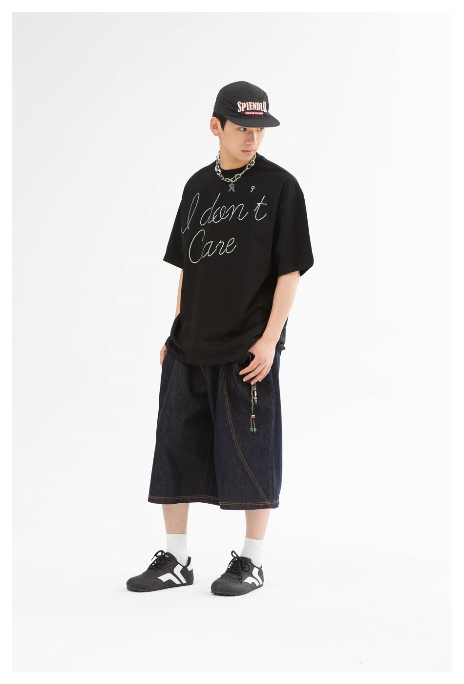Model wearing a black script-print T-shirt and dark indigo wide-leg denim shorts, shown from the front.