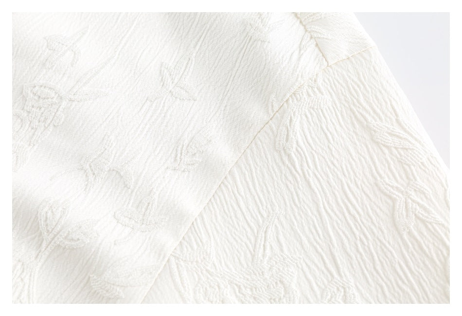 Close-up of white raised floral-patterned fabric and a diagonal stitched seam.