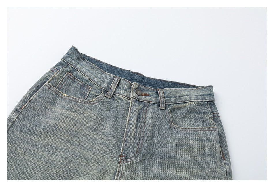 Angled close view of the faded blue jeans' front waistband, belt loops, button, fly and pockets.
