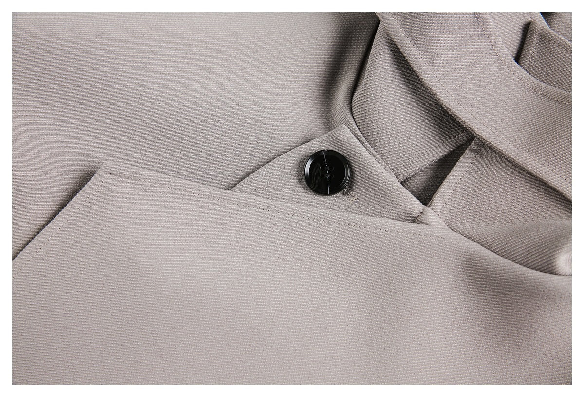 Close-up of light gray garment fabric and a black button fastening.