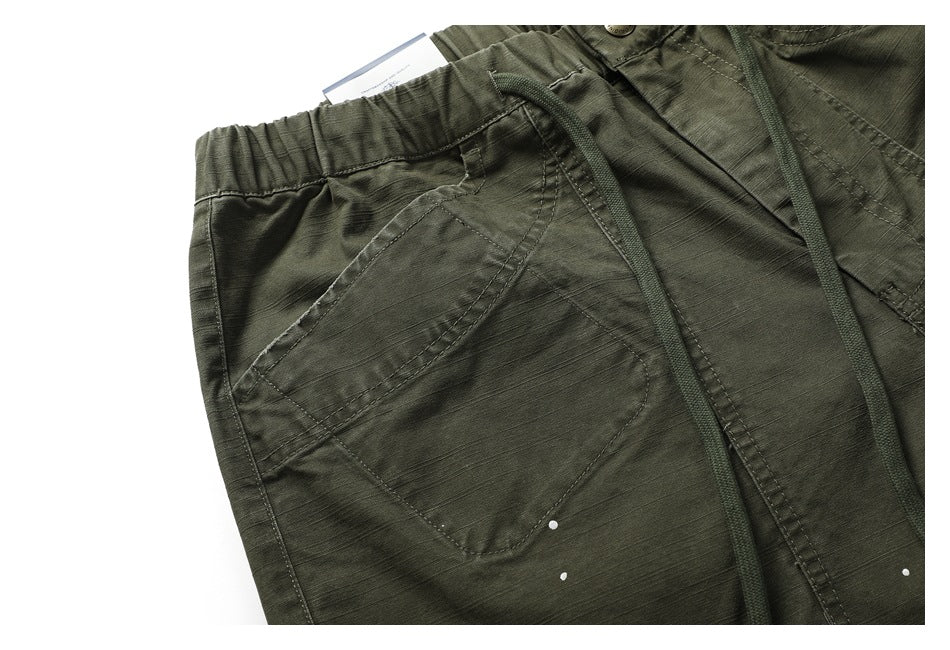 Close-up of the olive-green pants' elastic waistband, drawstrings and angled pocket stitching.