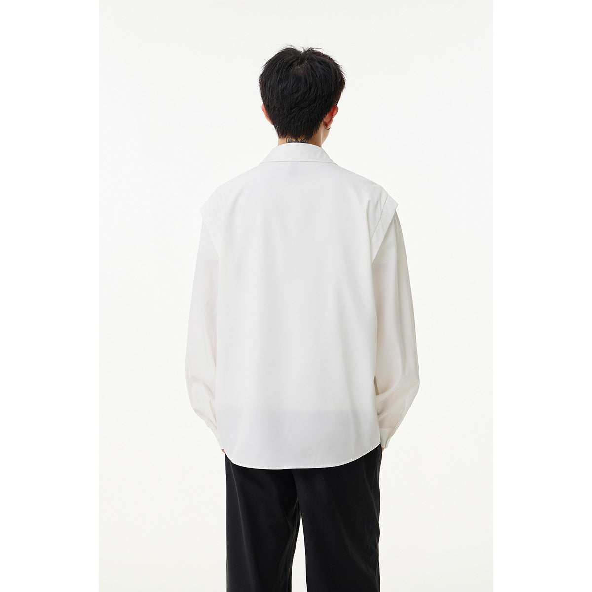 Rear view of a model wearing a white long-sleeve shirt with a wide back and shoulder details.