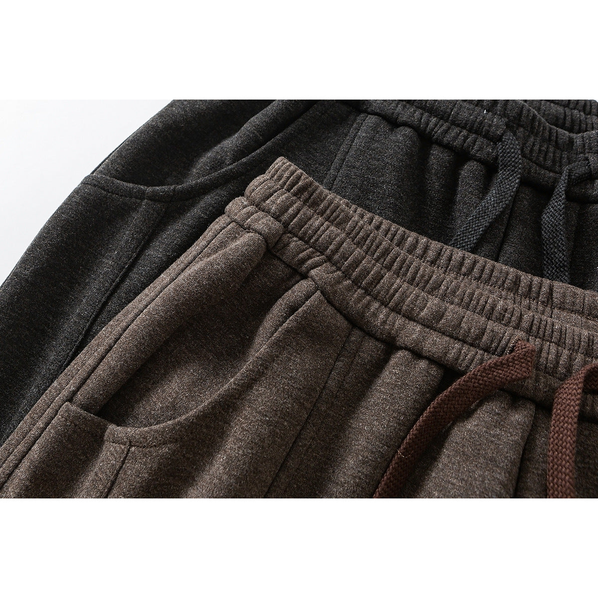 Close-up of brown and charcoal wide-leg pants showing elastic waistbands, drawstrings, and pocket openings.