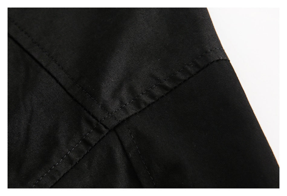 Close-up of intersecting stitched seams on black garment fabric.