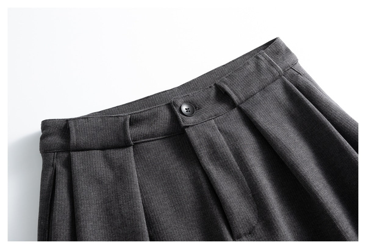 Close-up of charcoal gray trousers showing the waistband, button, and front pleats.