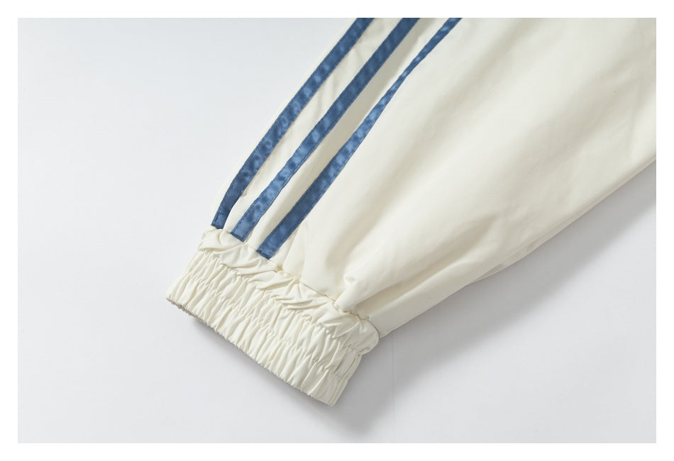 Close-up of an ivory sleeve with three blue stripes and a gathered elastic cuff.