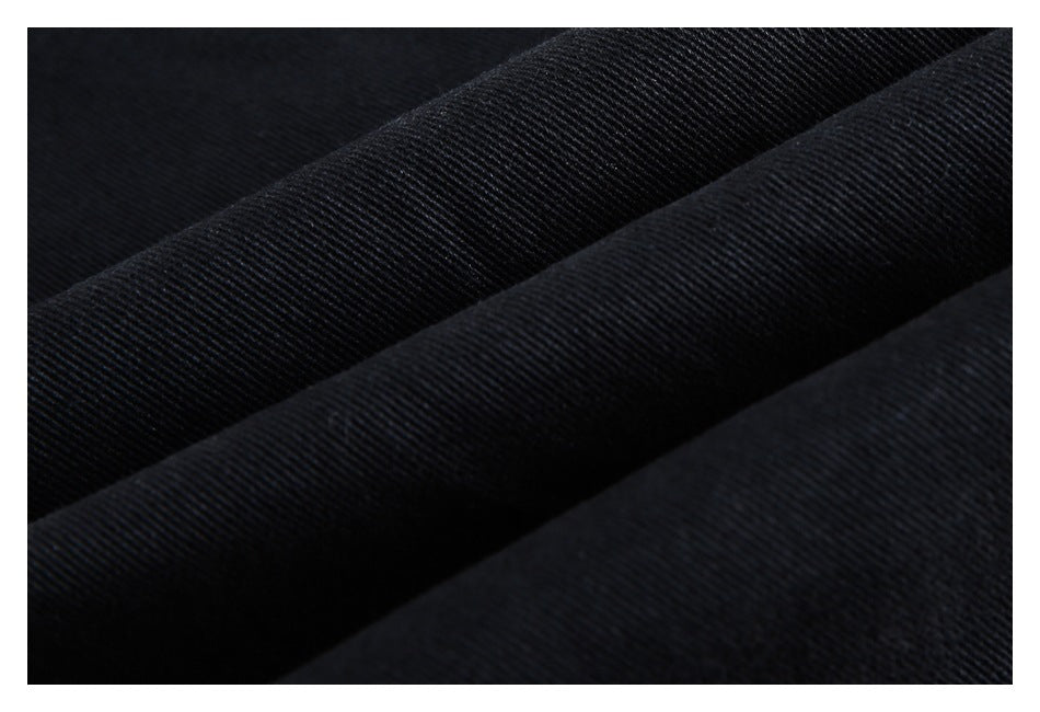 Macro view of the dark diagonal weave and texture of black trouser fabric.