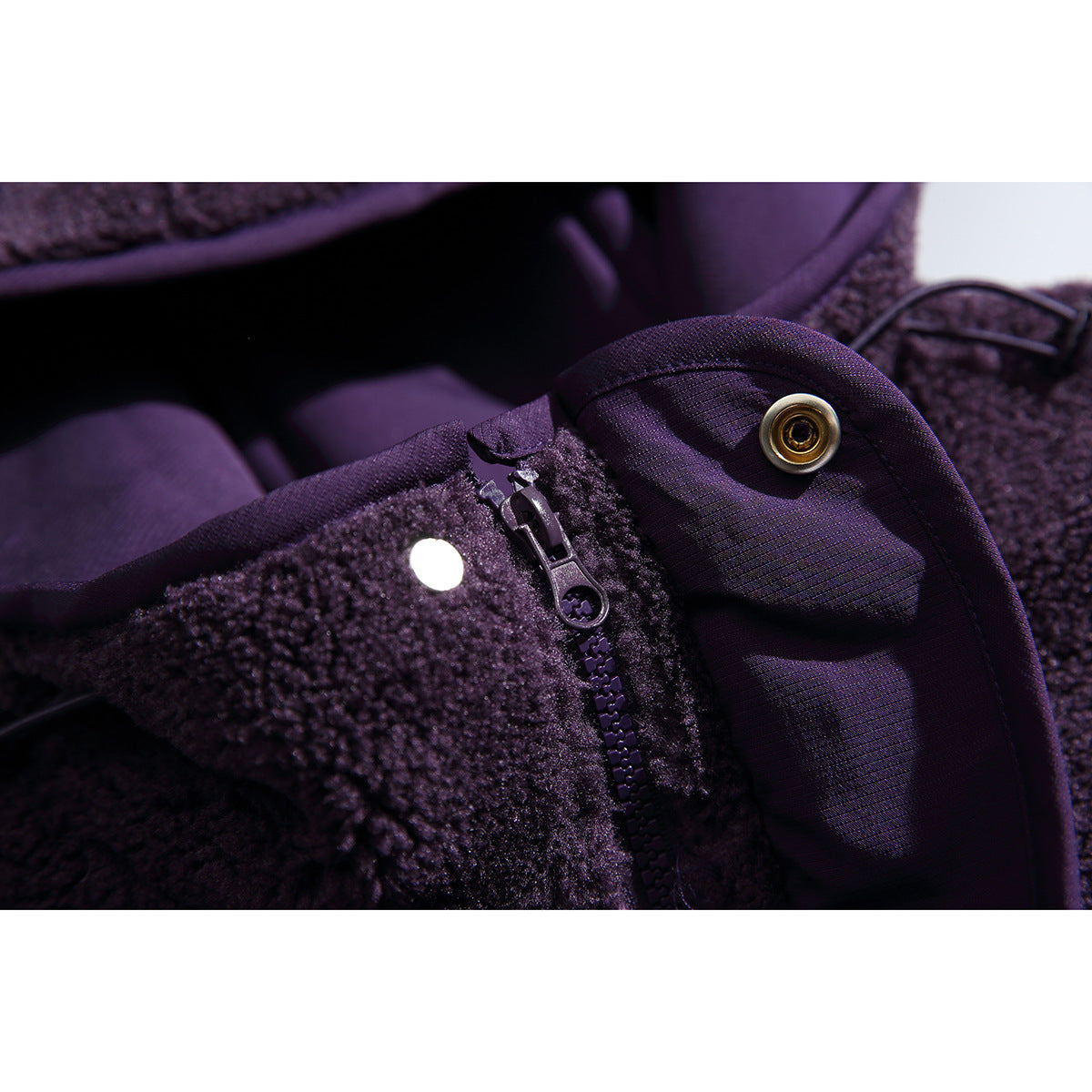Close-up of the purple jacket's zipper, snap fastener and contrasting woven trim.