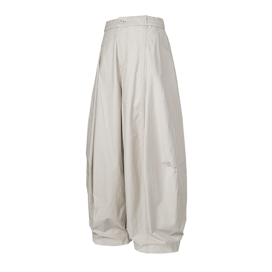 Front view of pale gray-beige wide-leg pants with a button waist, elasticated side panels, and cuffed hems.