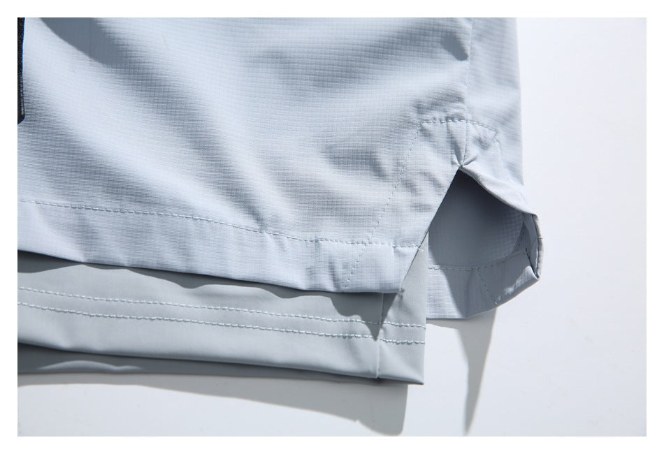 Close-up showing the stitched hem and side vent of pale blue-gray shorts.
