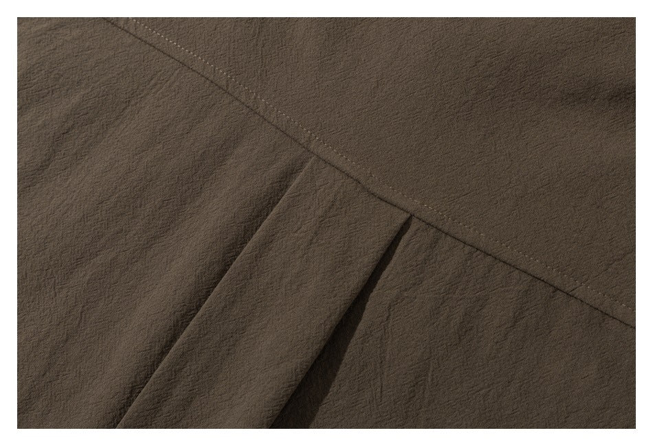 Close-up of a stitched seam and folded fabric detail on the brown shirt.