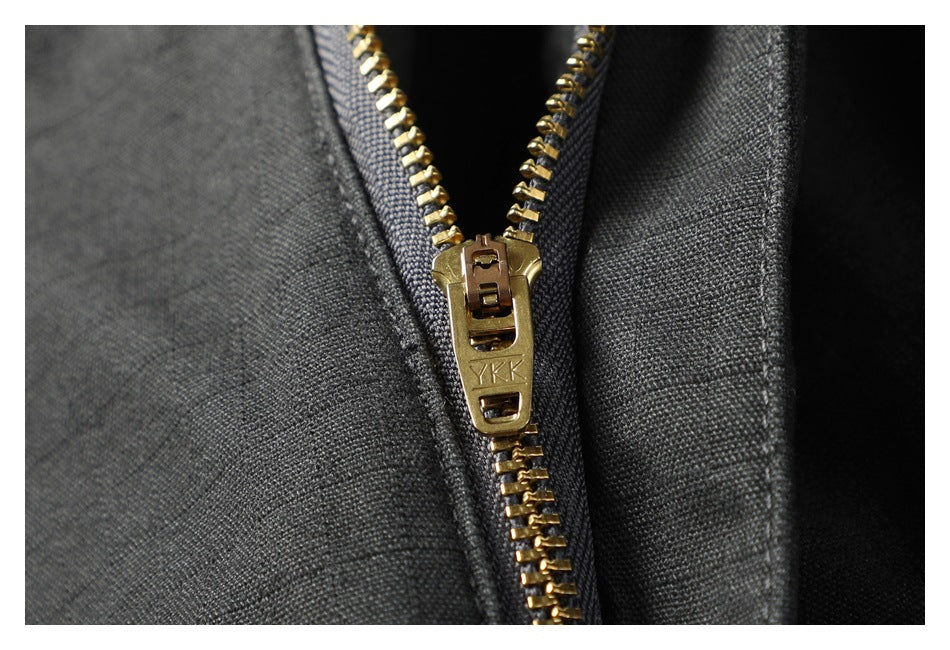 Close-up of a brass-colored YKK zipper on charcoal trouser fabric.