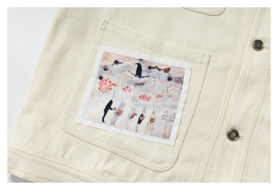 Cream jacket pocket with a pastel illustrated patch of small figures hanging beneath clouds.