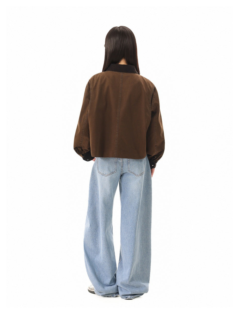 Rear view of a model wearing a brown cropped jacket with a dark collar and light blue wide-leg jeans.