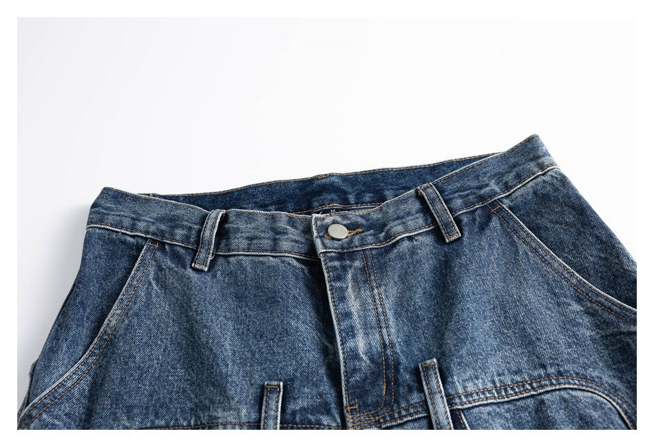 Cropped flat-lay view of the front upper section of blue washed jeans, including the waistband, button and pockets.
