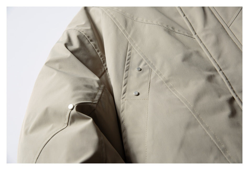 Close-up of a light taupe jacket sleeve and front panel with stitched seams and metal snap details.