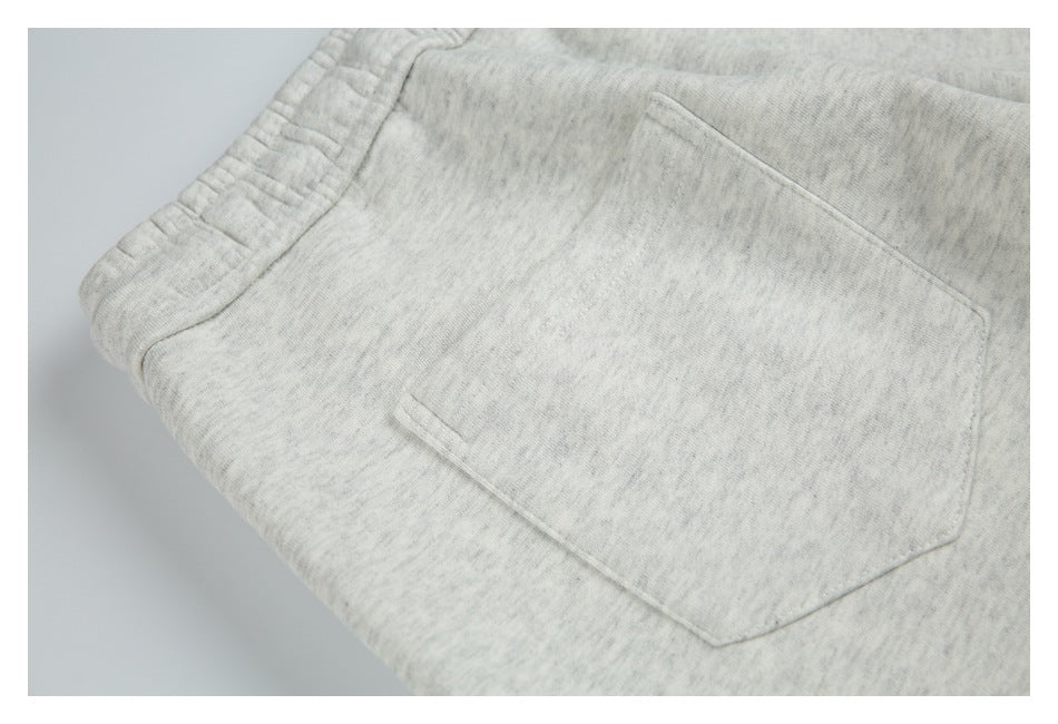 Close-up of a rear patch pocket and elastic waistband on light heather gray shorts.
