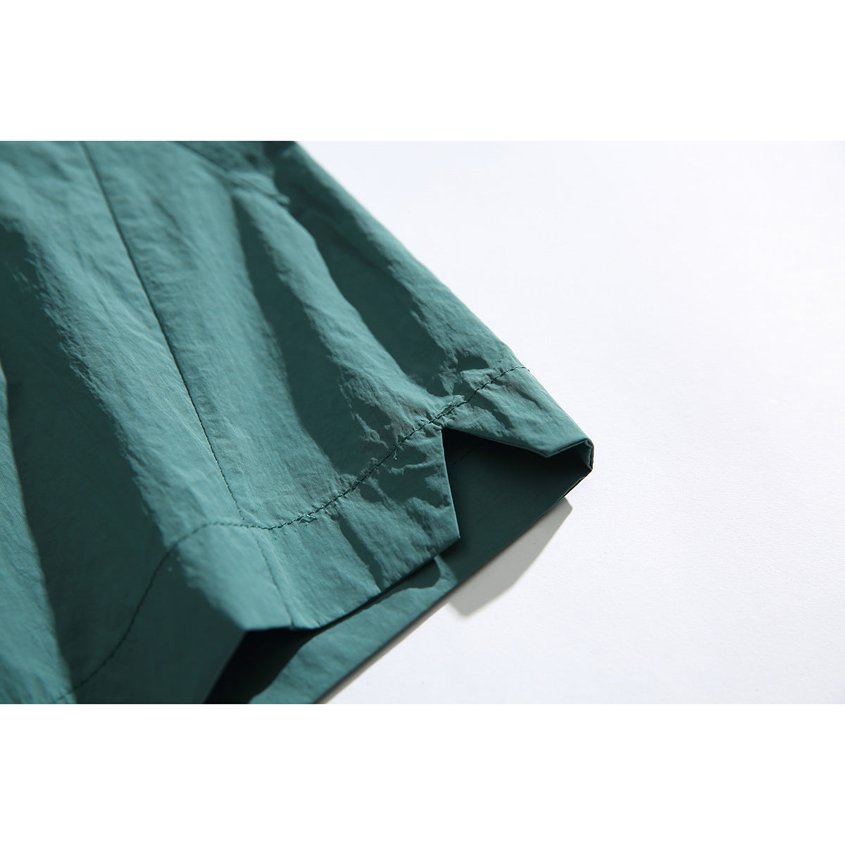 Close-up of the teal shorts' stitched hem and side seam.