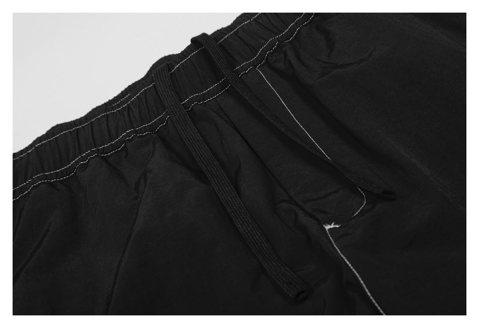 Close-up of the black pants' elastic waistband and drawstring with contrasting light stitching.