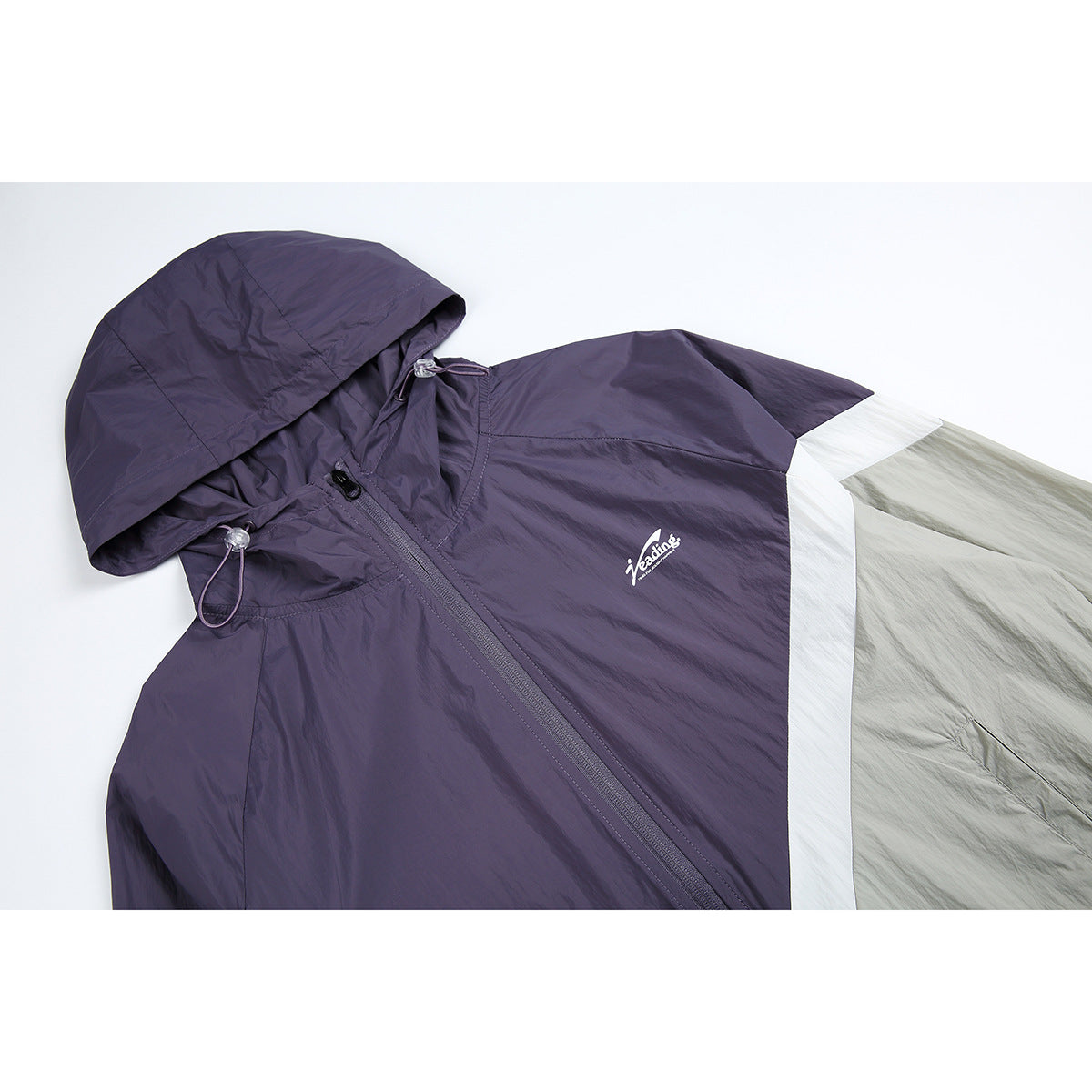 Close-up of a purple and light gray hooded jacket with a white colorblock stripe, front zipper, drawcords, and chest logo.