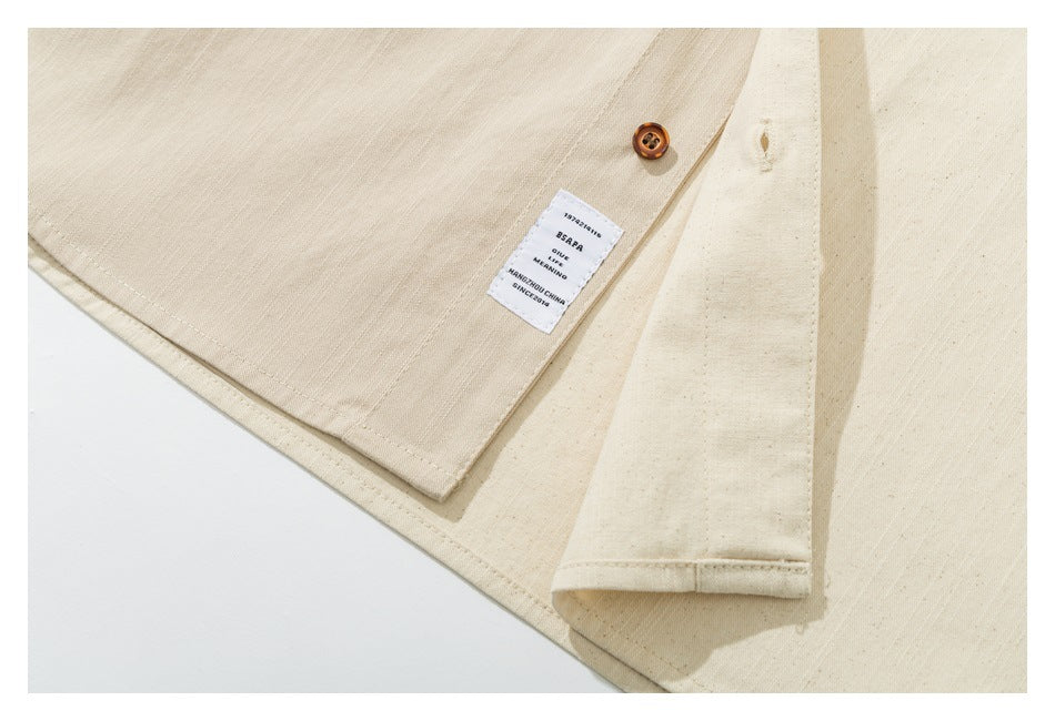 Close-up of a cream garment's inside seam, button, cuff, and small fabric label with English text.