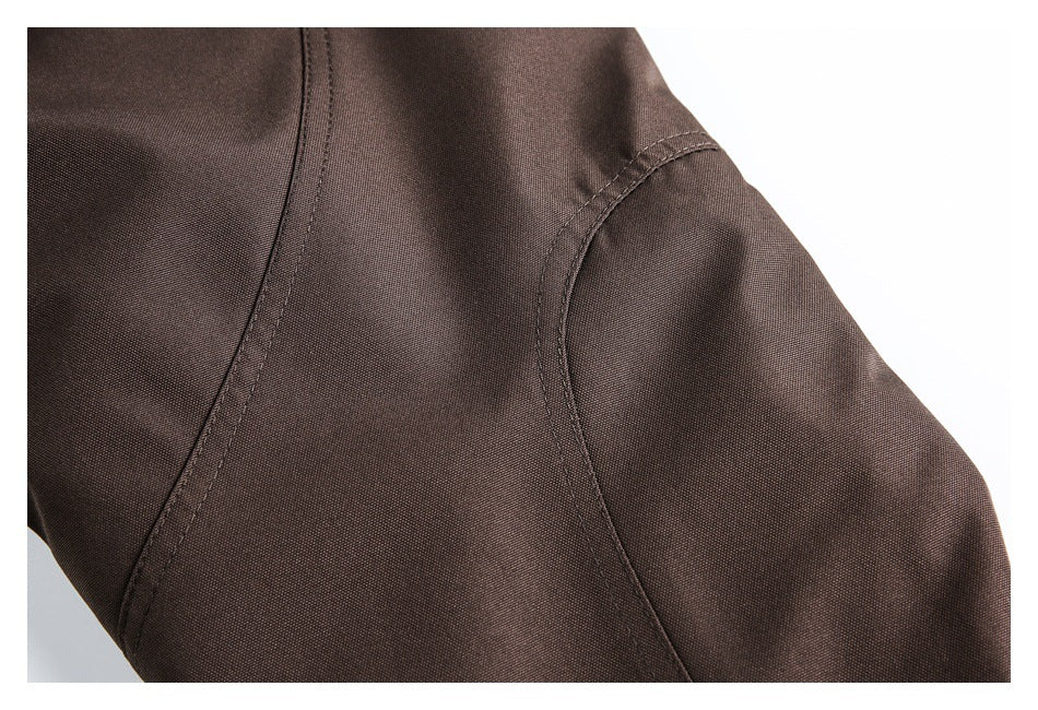 Close-up of brown garment fabric and curved stitched seam at a sleeve or panel.