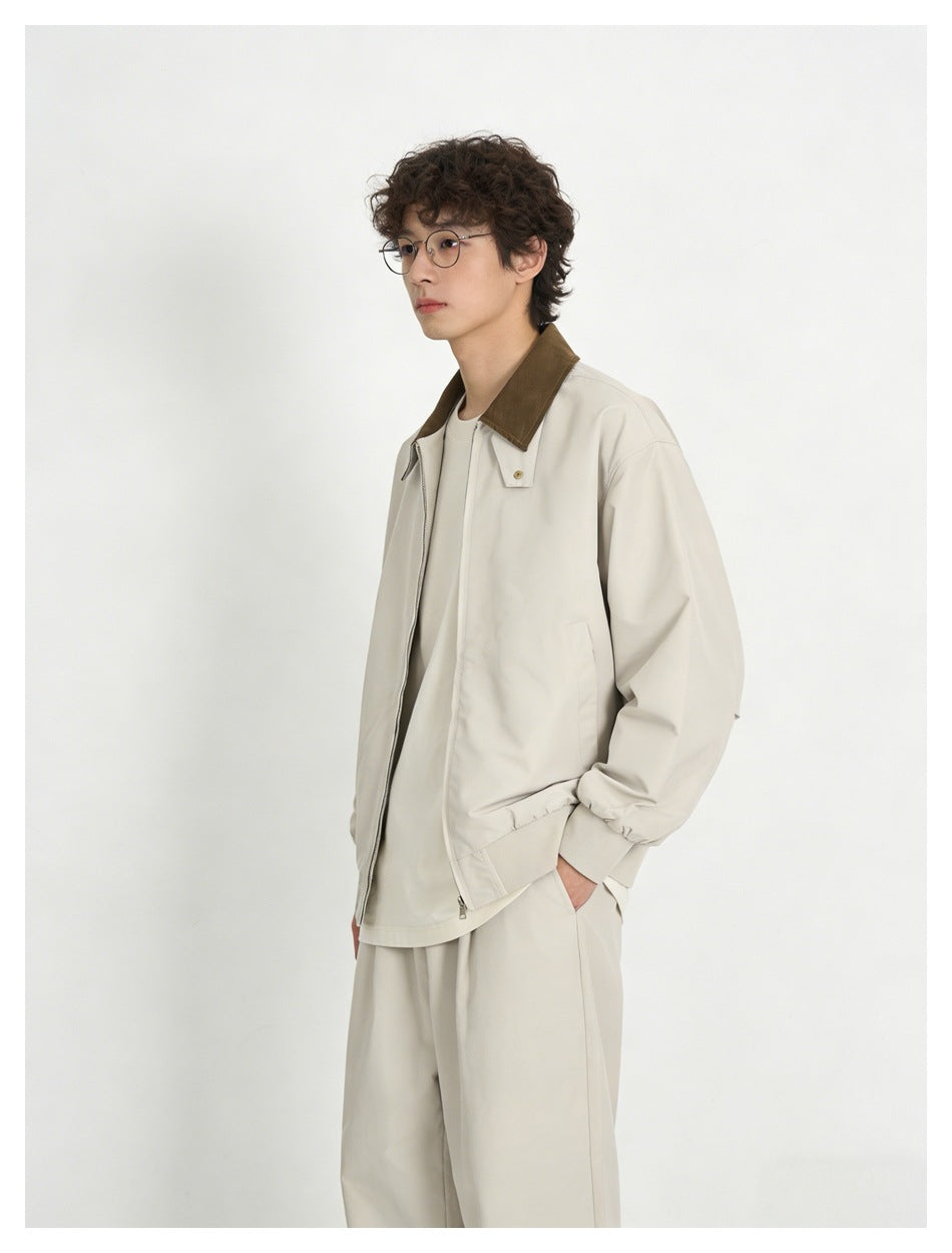 Angled view of a model wearing a light cream zip jacket with a brown collar and matching trousers.