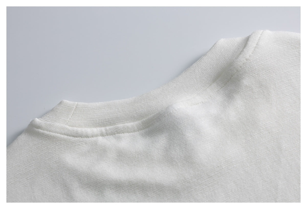 Close-up of a white garment's round neckline and shoulder seam.