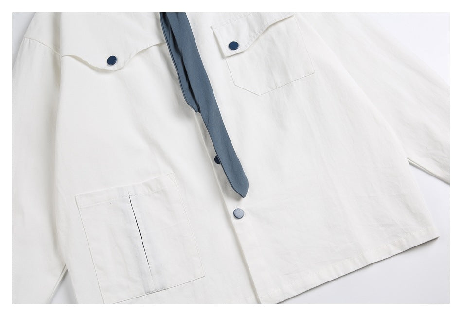 Close-up of the white shirt's front pockets, blue buttons, and blue necktie.