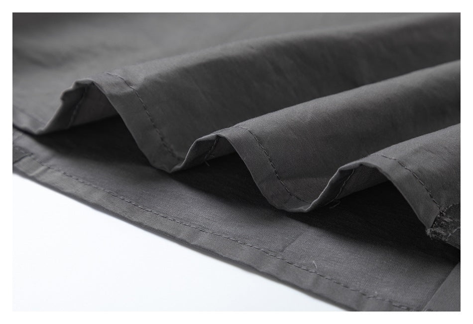 Close-up of a charcoal garment hem with folded fabric and visible stitching.
