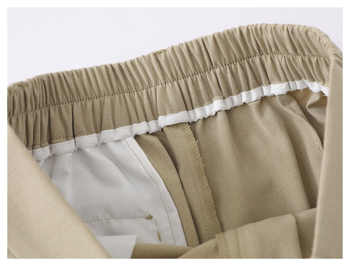 Inside view of beige trousers showing a gathered elastic waistband, white lining, and seam finishing.