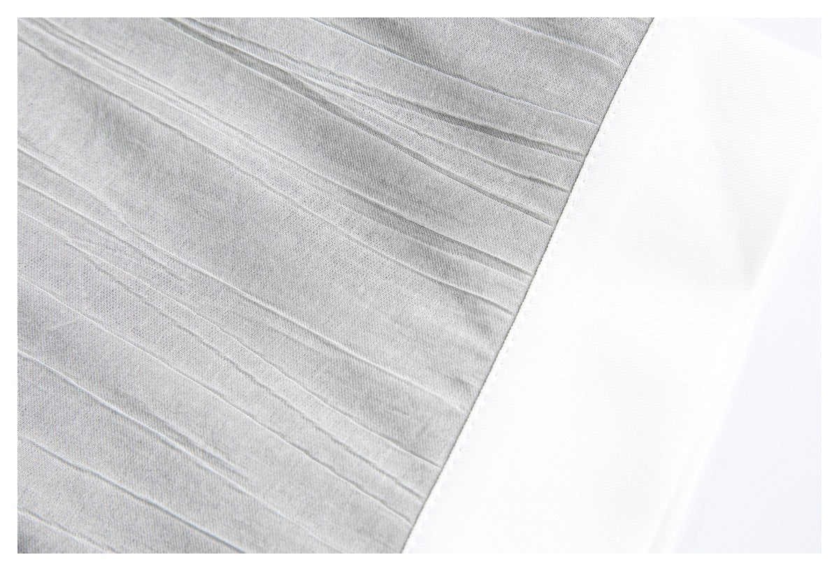 Close-up of raised lines on gray fabric meeting a broad white panel.