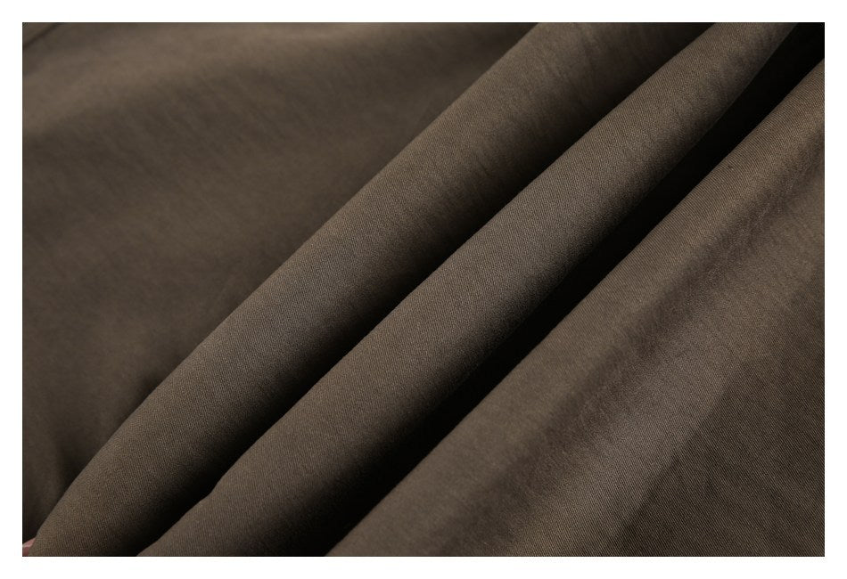 Close-up of brown garment fabric arranged in folds, showing its surface and drape.