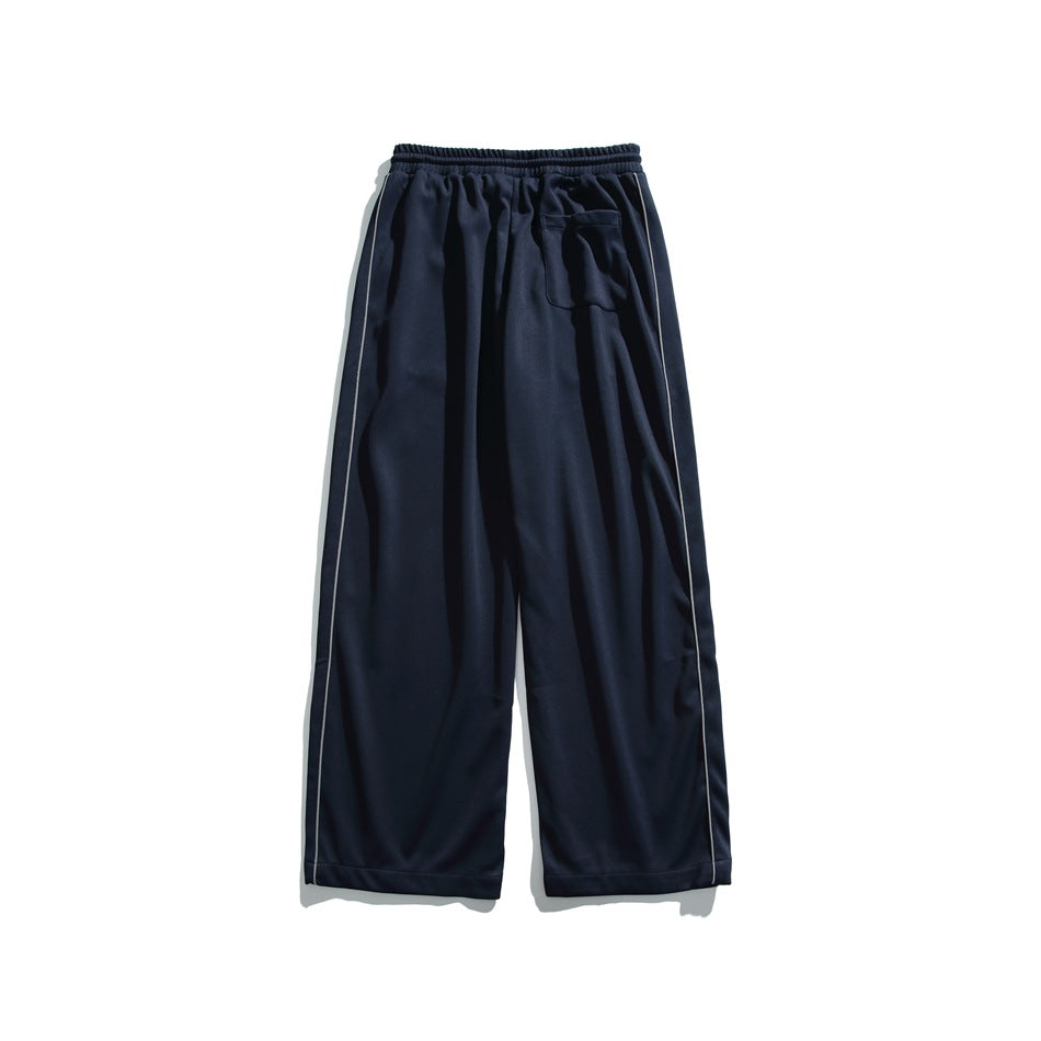 Navy wide-leg pants shown from the back, with an elastic waistband, single patch pocket, and pale piping along the sides.