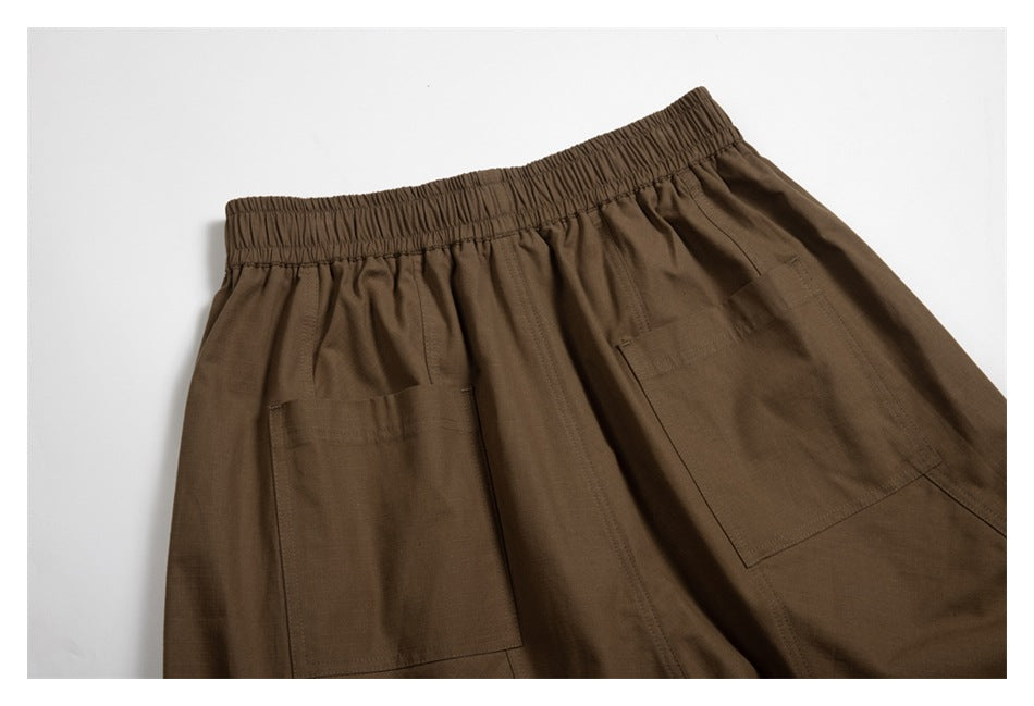 Cropped flat lay of brown trousers showing an elastic waistband and two rear patch pockets.