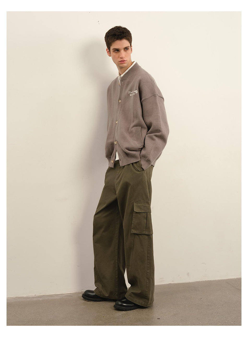 Model in a taupe button-front cardigan with chest embroidery and olive cargo pants, shown at an angle.