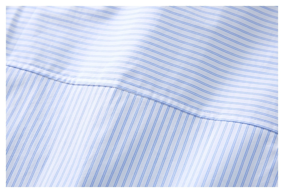 Close-up of a white shirt with fine blue stripes, showing a stitched fabric panel and seam.