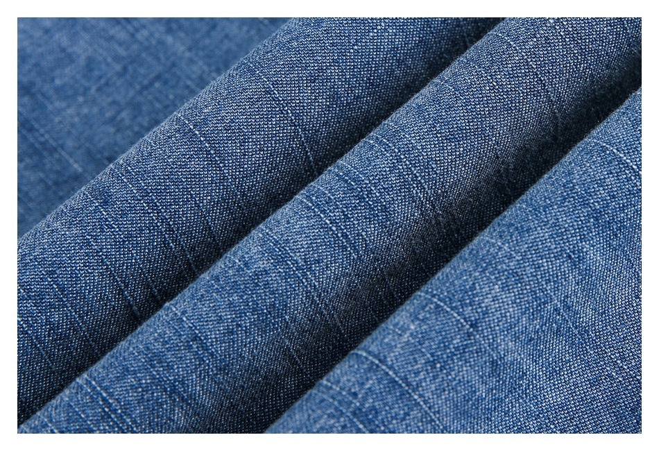 Close-up of blue denim fabric arranged in folds, highlighting its woven texture.