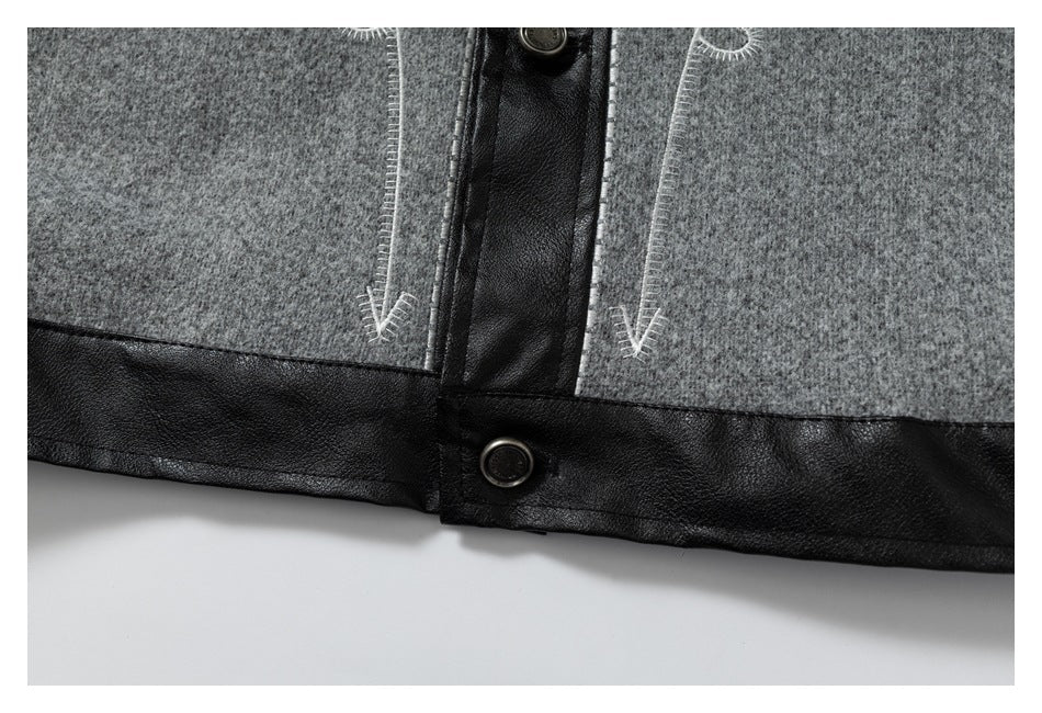 Close-up of a gray jacket hem with black trim, contrast stitching, and metal buttons.
