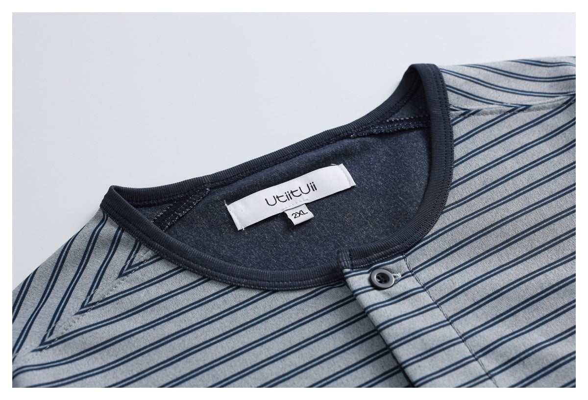 Close-up of a gray-blue striped top’s dark ribbed neckline, button placket, and sewn neck label.