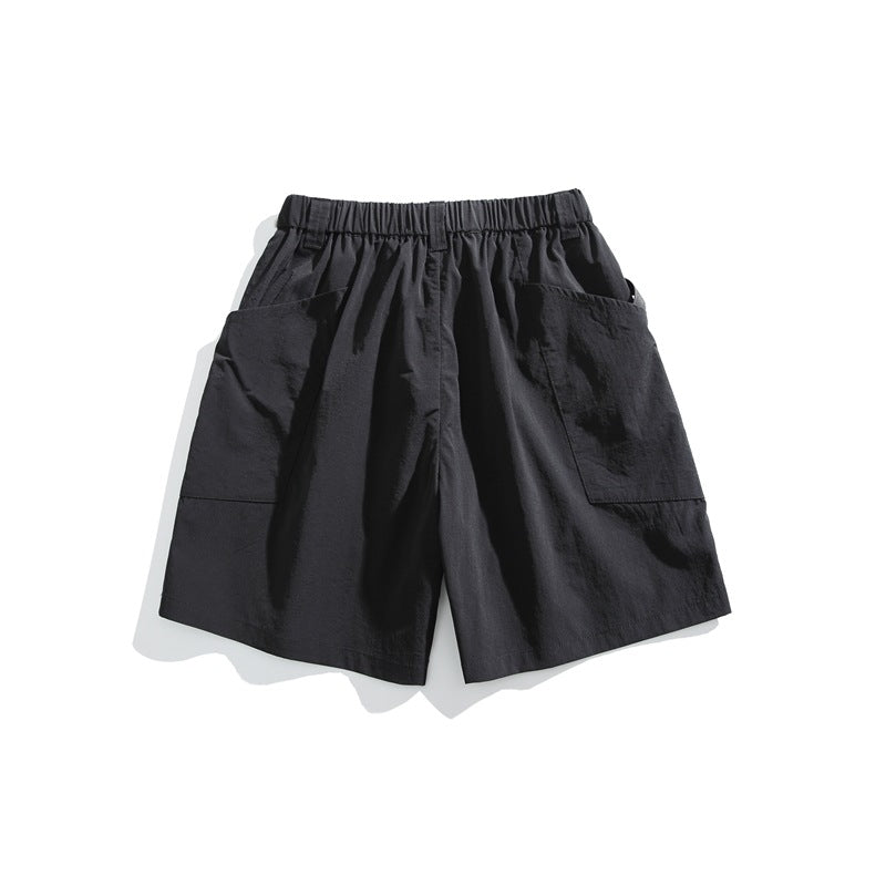 Black shorts with an elastic waistband and large patch pockets on both sides, shown against white.