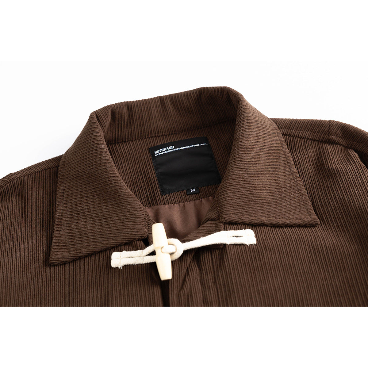 Close-up of a brown ribbed jacket collar, cream toggle closure, and black neck label.