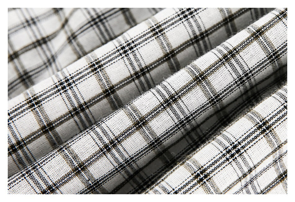 Macro view of white fabric with a black and gray plaid weave, arranged in soft folds.
