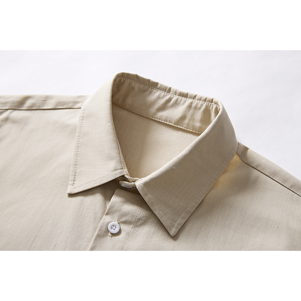 Close-up of a beige short-sleeve shirt showing its pointed collar, white button, and front placket.