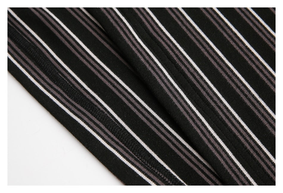 Close-up of a seam on black fabric with narrow white and muted mauve stripes.