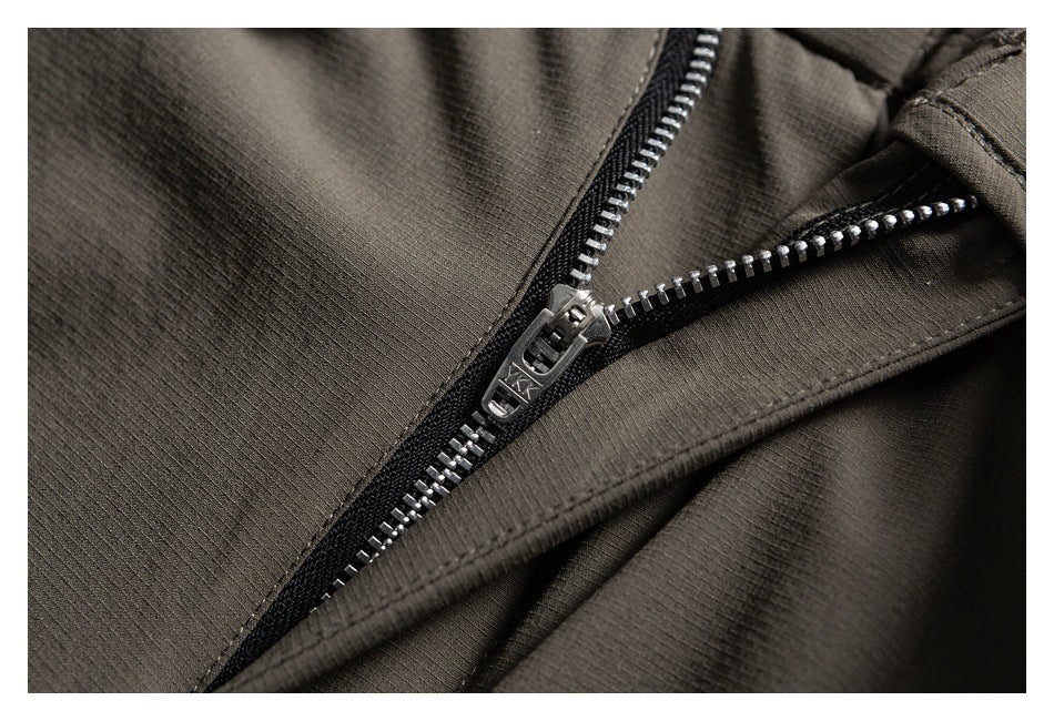 Close-up of a metal zipper on olive-gray fabric, with black zipper tape and a metal pull.