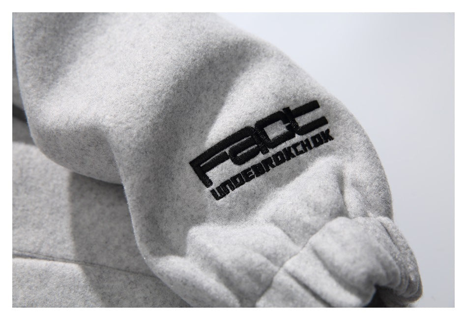 Close-up of a black embroidered logo on the light gray sleeve of a coat.
